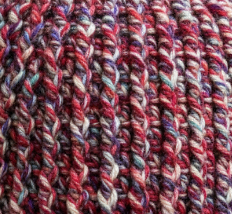 Close up of Firecracker Confetti crochet beanie ribbed stitch pattern in marled red and cream yarn highlighting thick textured construction for extreme cold weather wear
