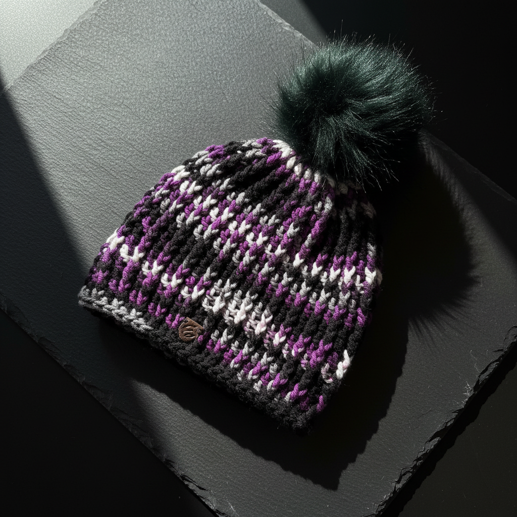 After Dark™ Classic Rib™ handmade crochet beanie in black, purple, and silver with oversized dark pom Flat Lay Studio