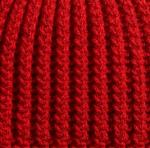 Close-up of a bright red ribbed crochet fabric texture.