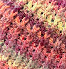 Ember Harvest crochet beanie close up of ribbed stitch detail in sunset orange, rust, and golden yarn highlighting thick textured construction for cold climate winter warmth