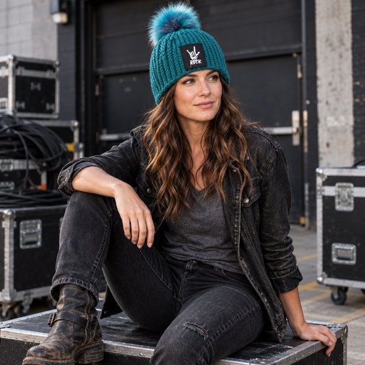 Rock Anthem™ No. 11 teal handmade Classic Rib™ beanie with Flat Head Crown™, blue faux-fur pom and black ROCK hand-horns patch, shown worn backstage.