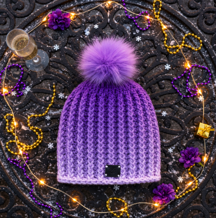 Purple Ombre crochet beanie on mardi gras decorated metal tabletop with beads and twinkle lights